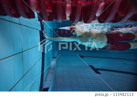 Underwater view of swimmer in red cap reaching edge of pool. Young man in motion, training, developing speed 113482113