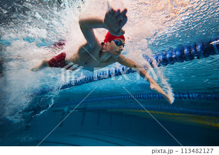 Water bubbles demonstrating speed. Young man, swimming athlete in motion in pool training, preparing for competition 113482127