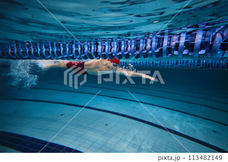 Power, concentration and resilience. Young athletic man, swimmer in motion, swimming freestyle in pool indoors, training 113482149