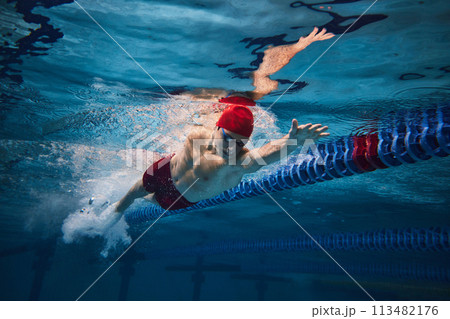 Powerful strokes. Freestyle swimming type. Young man, swimmer in motion training in swimming pool Powerful strokes. Freestyle swimming type. Young man, swimmer in motion training in swimming pool 113482176