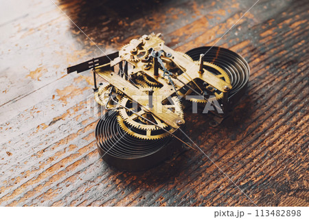 古い柱時計のゼンマイユニットが机の上に置かれている 113482898