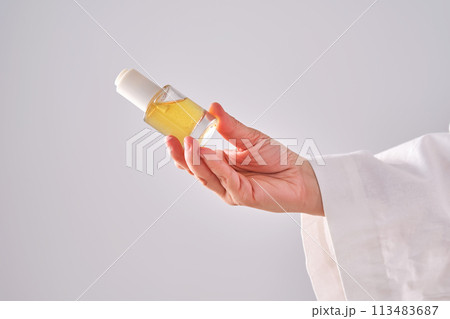 Blue serum with pipette in a womans hands in a robe. 113483687