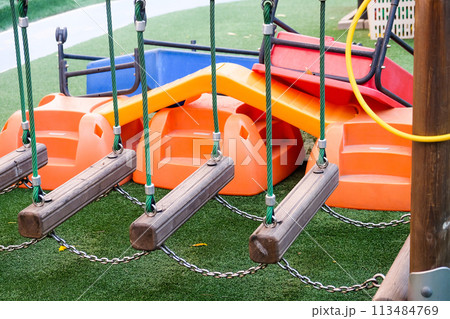 Empty playground with various equipment and toys on green synthetic grass Empty playground with various equipment and toys on green synthetic grass 113484769
