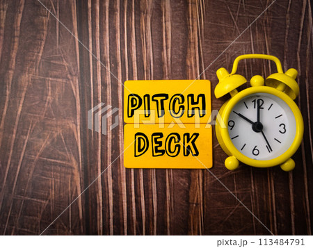 Top view clock and wooden board with text PITCH DECK on wooden background 113484791