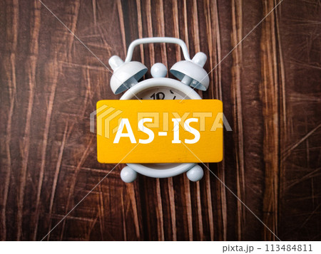 Top view clock and colored board with text AS IS on wooden background Top view clock and colored board with text AS IS on wooden background 113484811