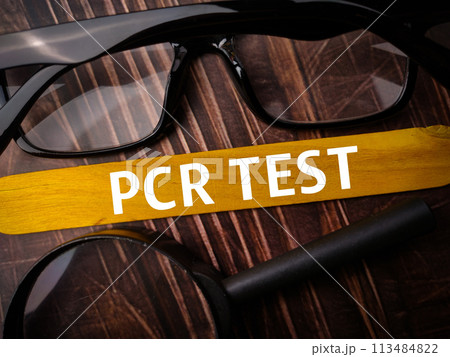 Top view padlock and calcuator with brown card with text PCR TEST on wooden background. 113484822