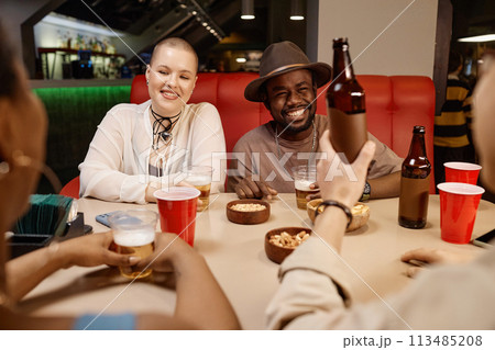 Diverse group of young people enjoying lunch together sitting at diner table 113485208