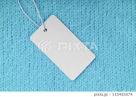 Template of blank clothing label, price tag on turquoise knitted sweater background 113485674