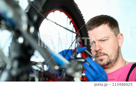 Male repair man bicycle service in blue protective 113486025