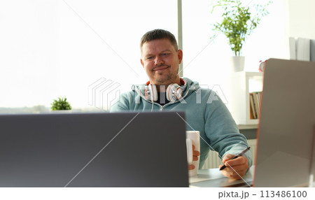 Handsome smiling male student using online Handsome smiling male student using online 113486100