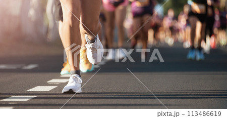 Marathon running in the light of morning. People feet on city road 113486619