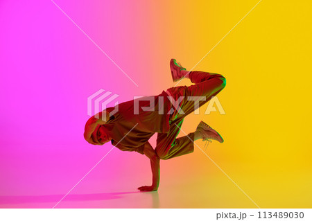 Dynamic photo of contemporary dancer dancing in freestyle in neon light against gradient pink-yellow background. 113489030