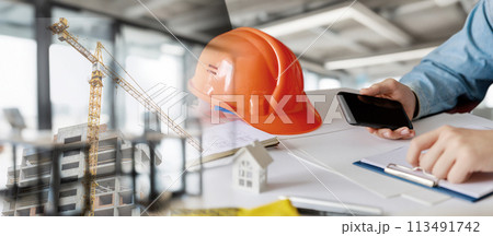 A builder is working in an office on a house project . A builder is working in an office on a house project . 113491742