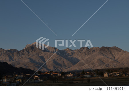 朝日が当たる南アルプス甲斐駒ケ岳の白き峰、麓の街並み 113491914