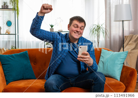 Surprised excited man holding smartphone reading good news amazed by online bet bid game win victory 113491966