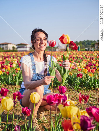 happy female workers trimming flowers in greenhouse 113492114