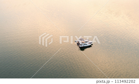 A solitary yacht on a calm lake or river at golden hour, evoking a sense of tranquility. 113492202