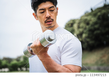 屋外でダンベルで筋トレをする男性 113497213
