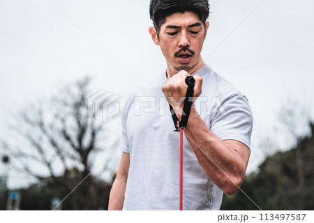 公園でトレーニングチューブで筋トレをする40代男性 113497587