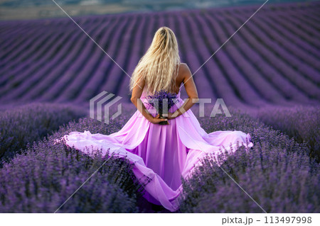 Back view woman lavender sunset. Happy woman in pink dress holds lavender bouquet. Aromatherapy concept, lavender oil, photo session in lavender 113497998