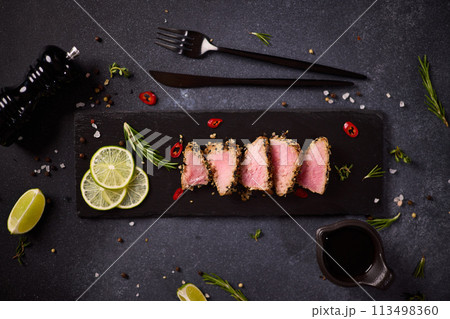 Sliced Organic grilled Tuna fillet covered with sesame seeds on black stone serving board Sliced Organic grilled Tuna fillet covered with sesame seeds on black stone serving board 113498360