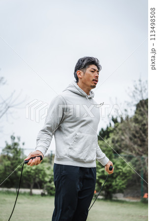 屋外でトレーニングする40代男性　縄跳び 113498508