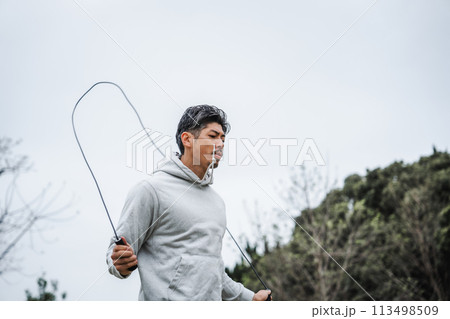 屋外でトレーニングする40代男性　縄跳び 113498509