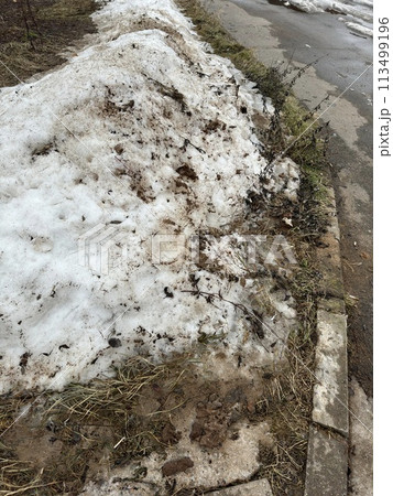 Melting dirty snow on the streets of the city during the daytime in winter. Snow with sand and mud lies on the road. Melting dirty snow on the streets of the city during the daytime in winter. Snow with sand and mud lies on the road. 113499196