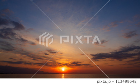 夕方の空に沈んでいく夕陽と、たくさんの雲 113499648