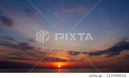 夕方の空に沈んでいく夕陽と、たくさんの雲 夕方の空に沈んでいく夕陽と、たくさんの雲 113499658