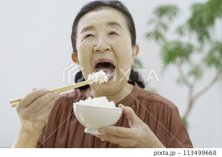 大きな口を開けて元気よく白米を食べるシニア女性 113499668