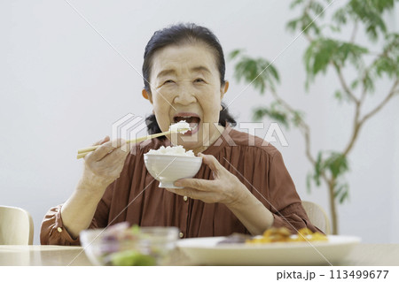 大きな口を開けて元気よく白米を食べるシニア女性 113499677