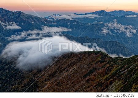 南アルプス・仙丈ヶ岳から見る残照の仙塩尾根に流れる滝雲と塩見・荒川の山並み 113500719