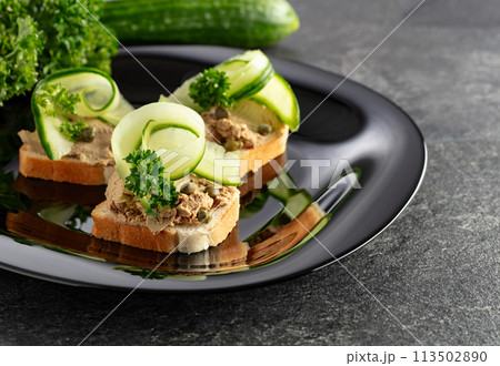 Open sandwiches with pate, fresh cucumber, capers, and parsley. 113502890