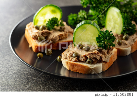 Open sandwiches with pate, fresh cucumber, capers, and parsley. 113502891