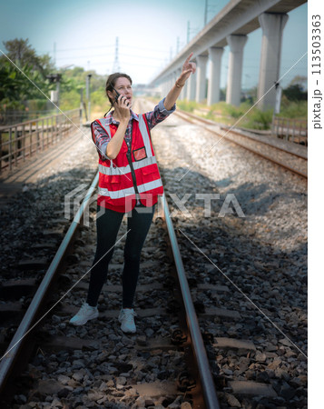 Woman railway engineer use walkie-talkie talking in to talk to maintenance department at site work of train garage. Woman railway engineer use walkie-talkie talking in to talk to maintenance department at site work of train garage. 113503363