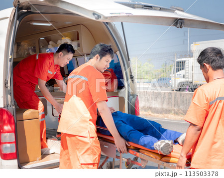 Paramedic in uniform  loading patient on stretcher into ambulanceworking together with team 113503378
