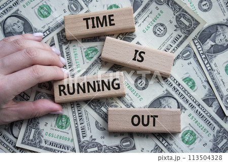 Time is running out symbol. Concept words Time is running out on wooden blocks. Beautiful dollar background. Businessman hand. Business and Time concept. Copy space. 113504328