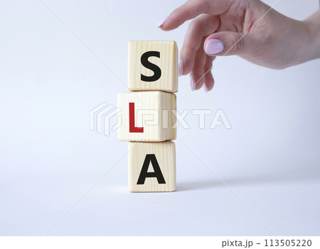 SLA - Service Level Agreement. Wooden cubes with word SLA. Businessman hand. Beautiful white background. Business and Service Level Agreement concept. Copy space. SLA - Service Level Agreement. Wooden cubes with word SLA. Businessman hand. Beautiful white background. Business and Service Level Agreement concept. Copy space. 113505220