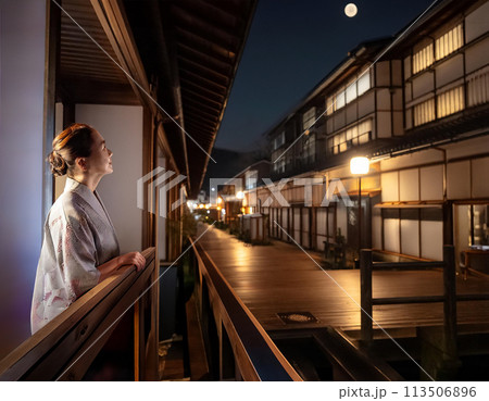 旅館街の夜景。女性が月を見ている 113506896