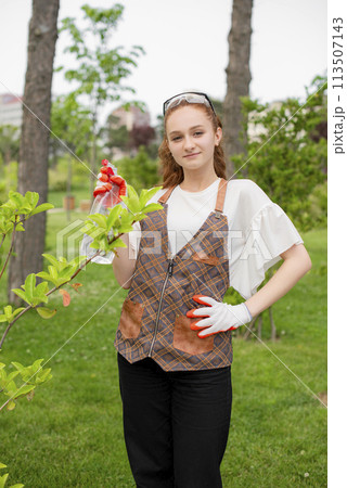 Front view of girl with red hair growing plants, looking at camera, smiling. Concept of taking care of plants. Front view of girl with red hair growing plants, looking at camera, smiling. Concept of taking care of plants. 113507143
