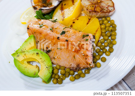 Tasty fried trout fillets, served with seashells, vegetables and avocado 113507351