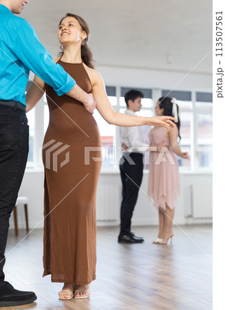 Girl and guy enjoying passionate latin american dancing with male partner in dance hall Girl and guy enjoying passionate latin american dancing with male partner in dance hall 113507561