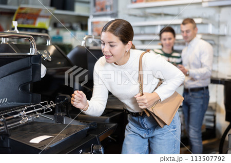 In store, girl inspects mobile grill, buys barbecue device In store, girl inspects mobile grill, buys barbecue device 113507792