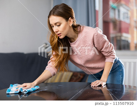 Young woman cleans table at home Young woman cleans table at home 113507910