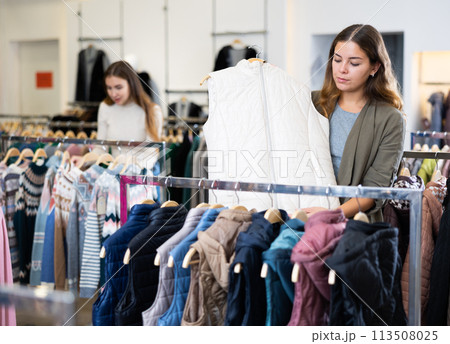 Young woman choosing insulated vest in store 113508025