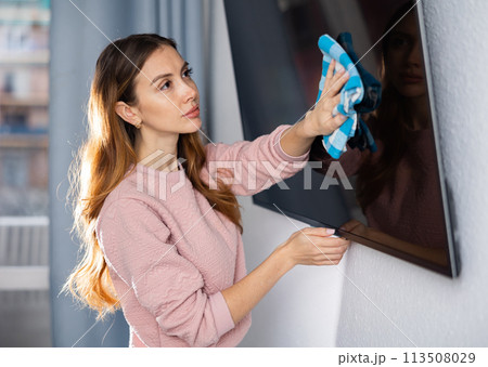 Woman is cleaning surface on the television at home 113508029
