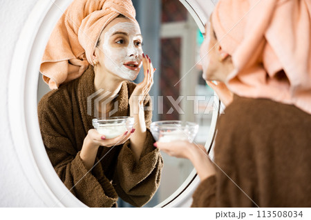 Happy woman taking care of face skin with lotion Happy woman taking care of face skin with lotion 113508034