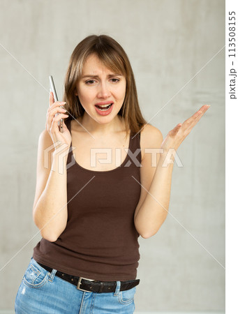 Indignant young girl talking on phone in studio Indignant young girl talking on phone in studio 113508155