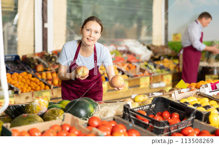 Smiling female vendor offering ripe apples at farmers market 113508269